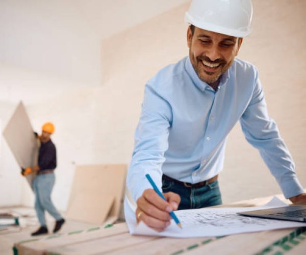 Happy housing project manager examining blueprints at construction site. Copy space.